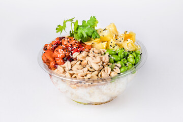 Poke bowl with rice, salmon, edamame beans, parsley, pineapple and peanuts on a white background. Plastic tableware for delivery. Close up.