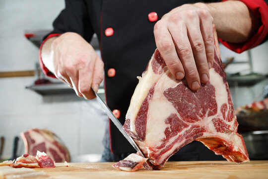 the chef is preparing a steak of aged meat. the chef cuts off a piece