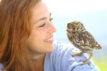 Happy woman with an owlet on her shoulder looks it