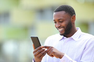 Happy man with black skin using smartphone outside