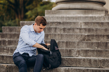 Handsome student sitting on stairs of university and studying