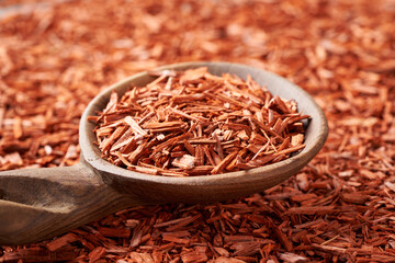 Pieces of red sandalwood on a wooden spoon - ingredient for aromatherapy essential oils