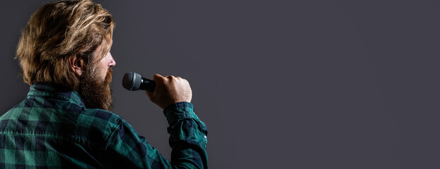 Bearded man in karaoke sings a song into a microphone. Male attends karaoke. Bearded man singing with microphone. Male singing with a microphones. Man with a beard holding a microphone and singing