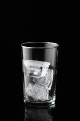 Ice cubes in empty glass on black background. Glass of water or whiskey and wine. Empty glass for alcoholic beverages