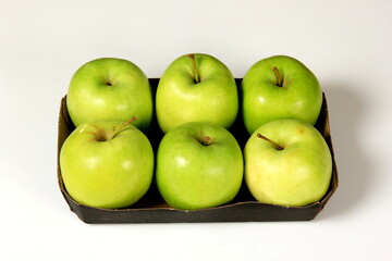 Six green apples in a packing box on a white background