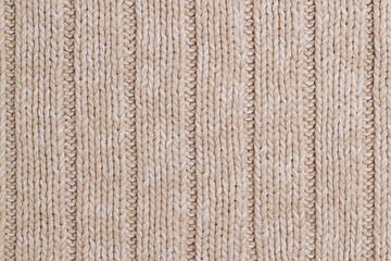 Fototapeta premium Beige knitted abstract background. Texture of a beige wool sweater.