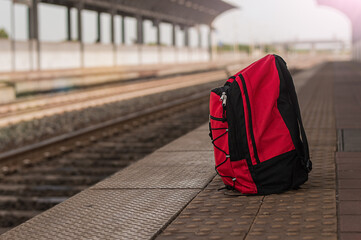 Red backpack against the background of a deserted railway station