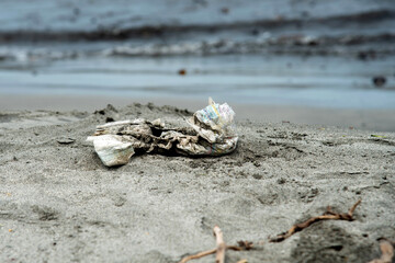 Dirty disposable baby diaper thrown on the sandy beach Diapers pollute the environment, destroying...