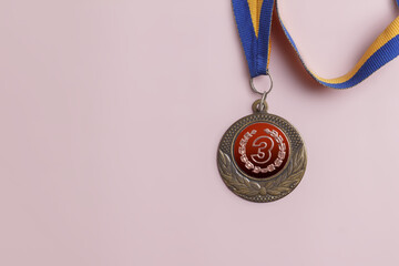 Bronze medal for 3rd place on a blue-yellow ribbon on a background with copy space.