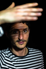 Young man covering himself from a light bulb.