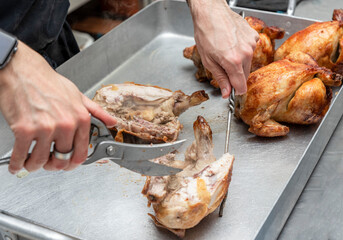 the hands of an unrecognizable cook slicing the roasted chicken