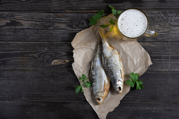 salted, dried vobla fish with amber beer on a dark wooden background with bread on table flat lay with copy space
