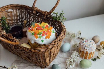 Fototapeta na wymiar Natural dyed easter eggs, easter bread, ham, beets, butter, cheese in wicker basket decorated with green buxus on rustic wooden table. Traditional Easter basket food
