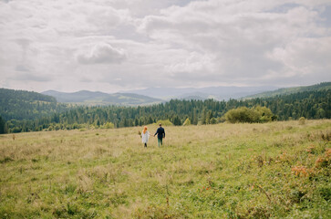 A loving young couple walks in the mountains and poses for the camera. Enjoy beautiful views, fresh air and be happy