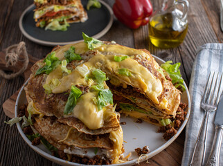Savory pancake stack, tex mex style with ground beef, beans, sour cream, lettuce, tomatoes and...