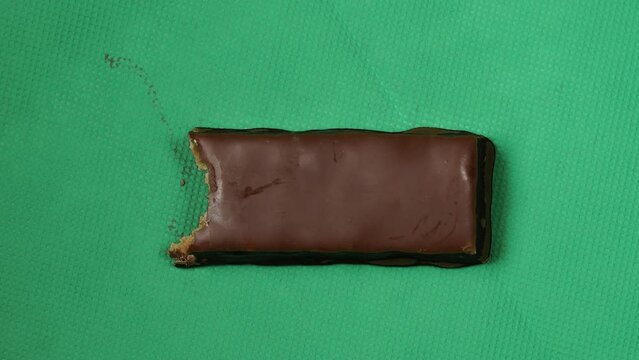 Stop motion of eating chocolate bar bite by bite, green background.