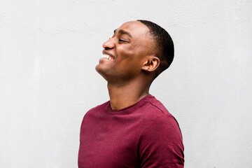 Close up profile happy young African American man laughing against gray background