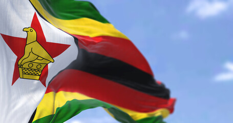 Detail of the national flag of Zimbabwe waving in the wind on a clear day.