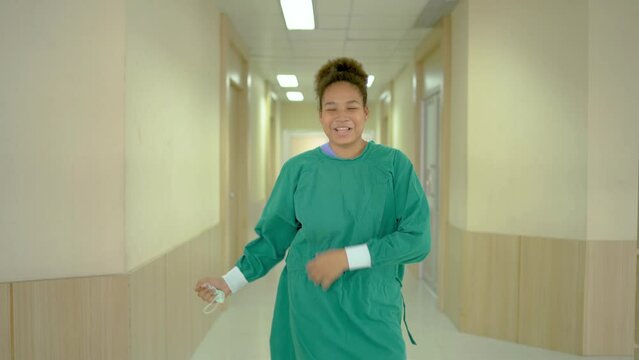Happy doctor, nurse and assistant smiling and dancing after successful do surgery, Funny surgical doctor dancing in front of the camera in a modern hospital corridor