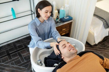 Beautician massaging mans head during hair treatment procedures