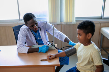 African pediatrician is measuring blood pressure and checking pulse child boy patient.