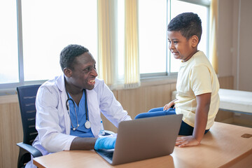 Obraz premium African pediatrician taking the patient's history and examining child boy patient.