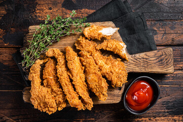 Crispy fried Breaded chicken strips, breast fillet meat with tomato ketchup on a plate. Wooden...