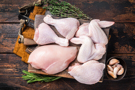 Assortment of chicken portions for Bbq grilling. Raw parts - drumstick, breast fillet, wings, thigh. Wooden background. Top view