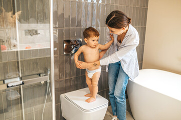 Mother leaning over her baby boy in the toilet
