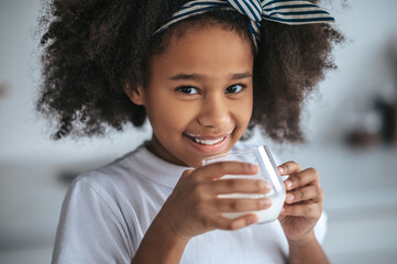 Cute dark-skinned girl with a glass of milk