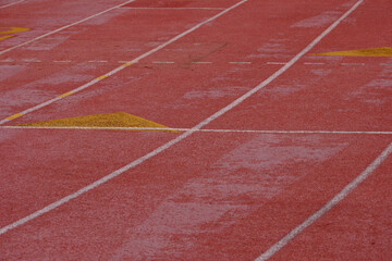 Fototapeta premium The red pavement and the starting grid for runners on a High School track