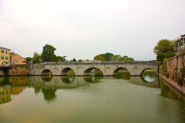 Fototapeta na wymiar Historical roman Tiberius Bridge over Marecchia river in Rimini, Italy