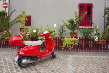 Fototapeta na wymiar Red scooter in picturesque San Giuliano district in Old Town of Rimini