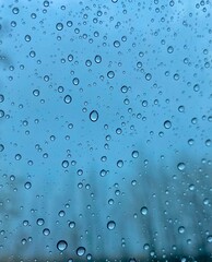 Blue drops of rain on a window glass in the city. Image of raindrops texture background. Water drops on glass for background, texture and wallpaper.