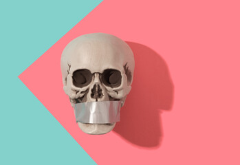 Skull with duct tape across the mouth on a pink and blue background. Speechless, lost for words...