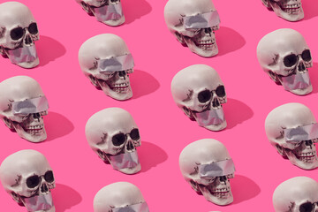 Human skulls with with duct tape over the eyes and mouth on a pink background. Freedom of speech...