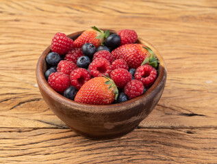 Strawberries, blueberries and raspberries in a bowl over wooden table