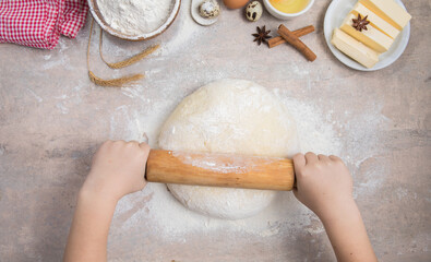 Baking cooking food ingredients. Child hands roll out the dough with a rolling pin on a silicone mat