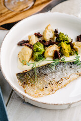 Sea bass with creamy lemon sauce and vegetables, cauliflower, broccoli, sun-dried tomatoes