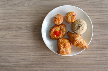 Mini homemade of Apple pie, Croissant, Spinach pie, Organic whole-wheat loaves, Almond muffins. place in a plate on a wooden table for serving  with hot beverages, coffee, chocolate, fresh milk.
