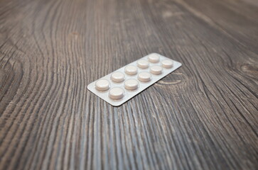 The blister of pills laying on the wooden table. The pills close up.