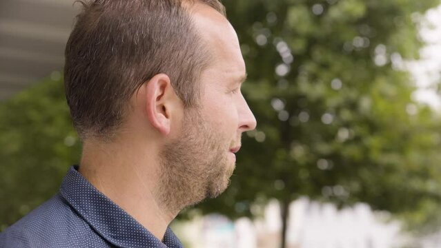 A Caucasian man looks off into distance in an urban area - closeup