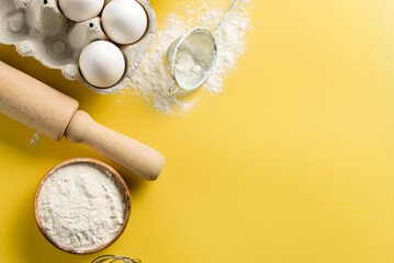 Ingredients and tools for home baking on a yellow background with copy space.