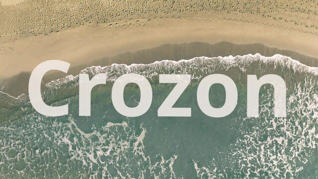 Shadow of a flying airliner reveals Crozon text on the sandy beach