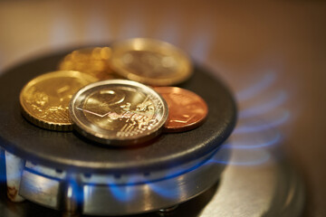 Shiny Euro coins on stove. Gas burning. Gas prices concept