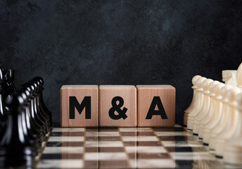Chessboard with chess pieces and wooden blocks with the word mergers and acquisitions