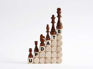 Chess pieces on the ladder of wooden cubes with the word update.