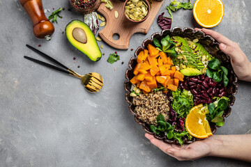 Quinoa salad in bowl with avocado, sweet potato, beans on gray background. superfood concept. Healthy, clean eating concept. Vegan or gluten free diet. top view