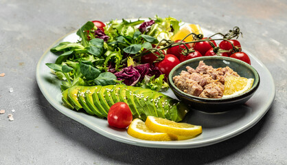 Ingredients for making Tuna fish salad on dark background. Lettuce, cherry tomatoes, avocado and red onions. Clean healthy detox eating. Vegan vegetarian food. Making healthy salad. top view