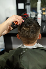 Teen guy gets a haircut during a pandemic at the barbershop, haircut and drying hair after a...